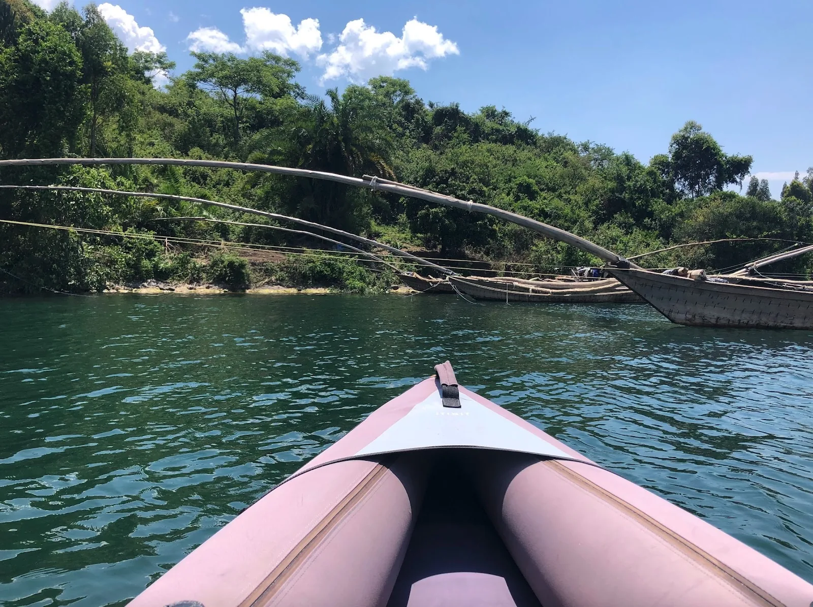 View from an inflatable kayak approaching a wooded shoreline on Lake Kivu.
